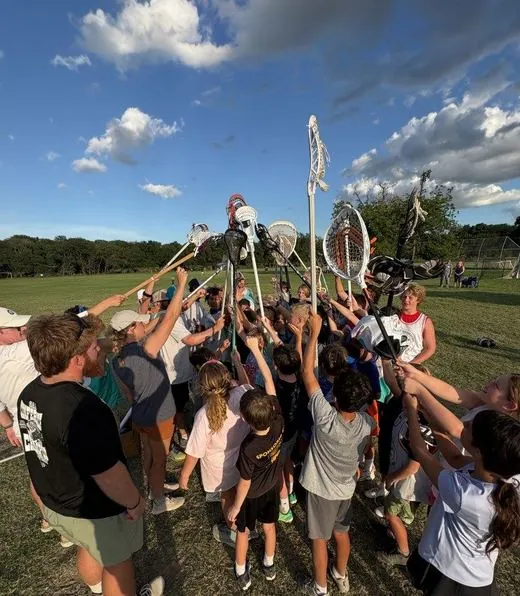 Team huddle with sticks raised at camp