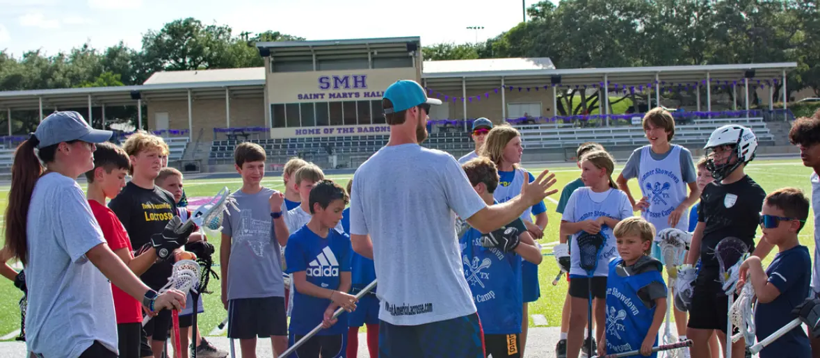 Coach instructing a group of young lacrosse players on the turf