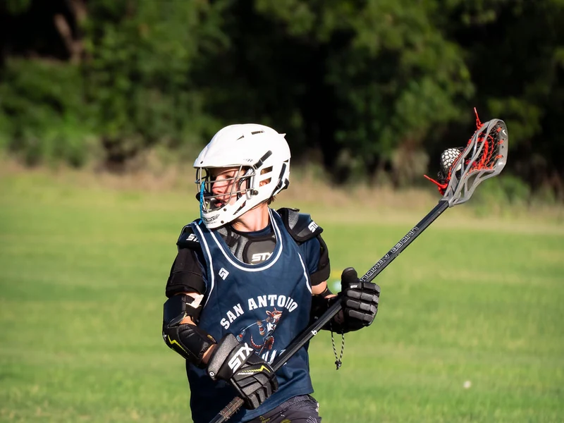 Young lacrosse player carrying the ball at a San Antonio clinic