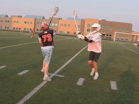 Two youth lacrosse players going one-on-one on the turf in San Antonio