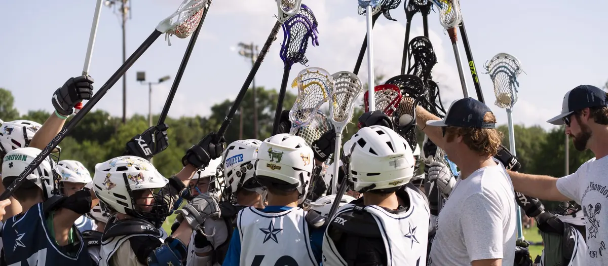 San Antonio Armadillos youth lacrosse team huddle with sticks raised