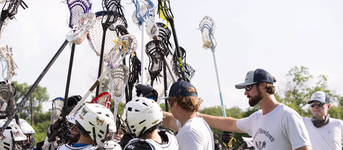 Coaches talking to a youth lacrosse team in a huddle