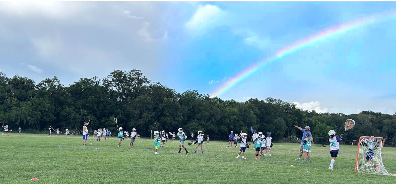 Youth lacrosse practice at Olmos Basin Soccer Fields in San Antonio under a rainbow